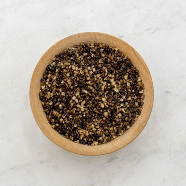 A small wooden bowl filled with Porcini Mushroom Sea Salt sits on a light, textured surface.
