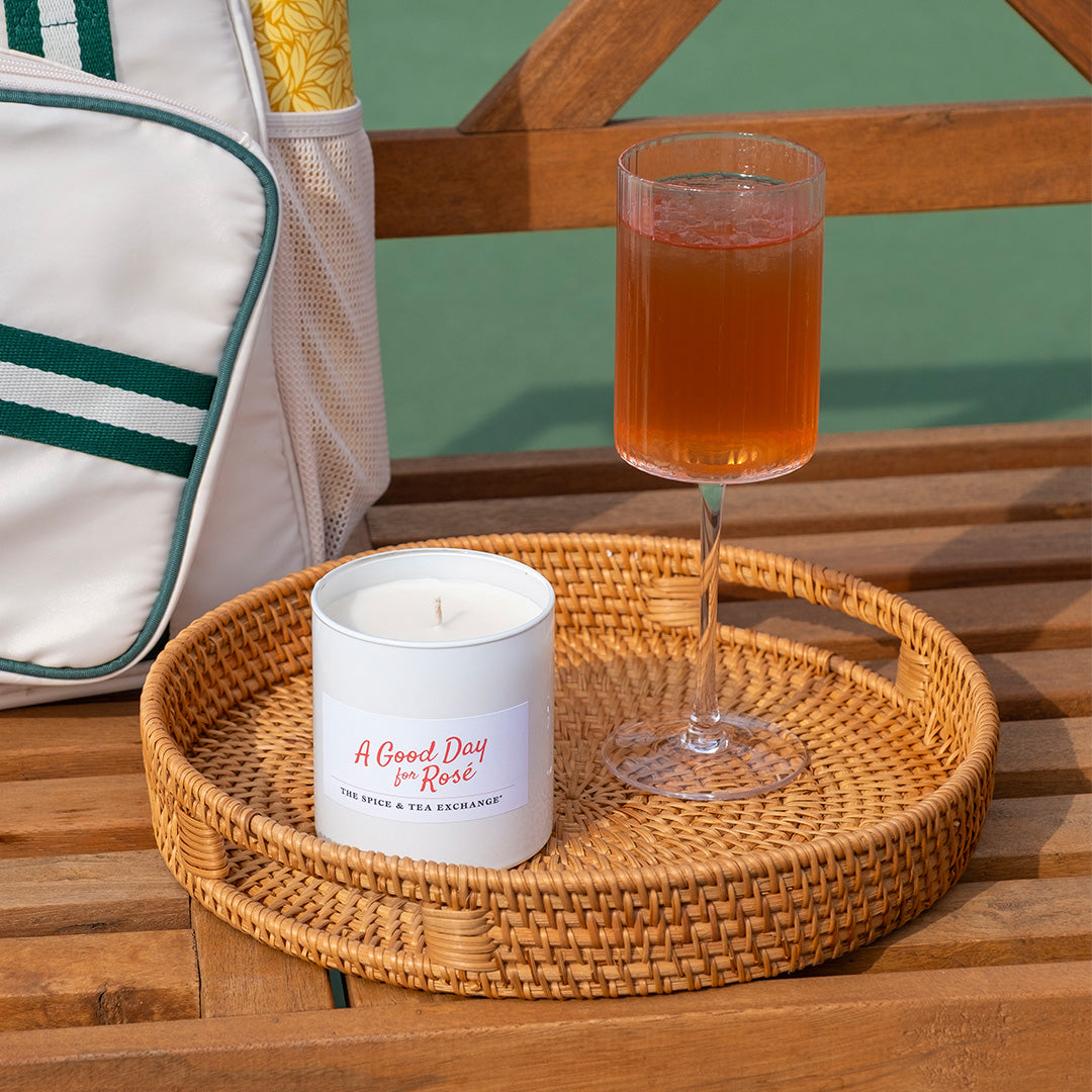 Candle and glass of tea on a woven tray with a bag in the background