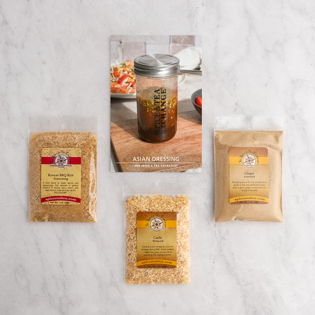 Three seasoning packets—Korean BBQ Rub, Ginger Powder, and Minced Garlic—are arranged around the Asian Dressing (Kit) booklet on a white surface, assembled as a vibrant kit ideal for making flavorful umami sauces.