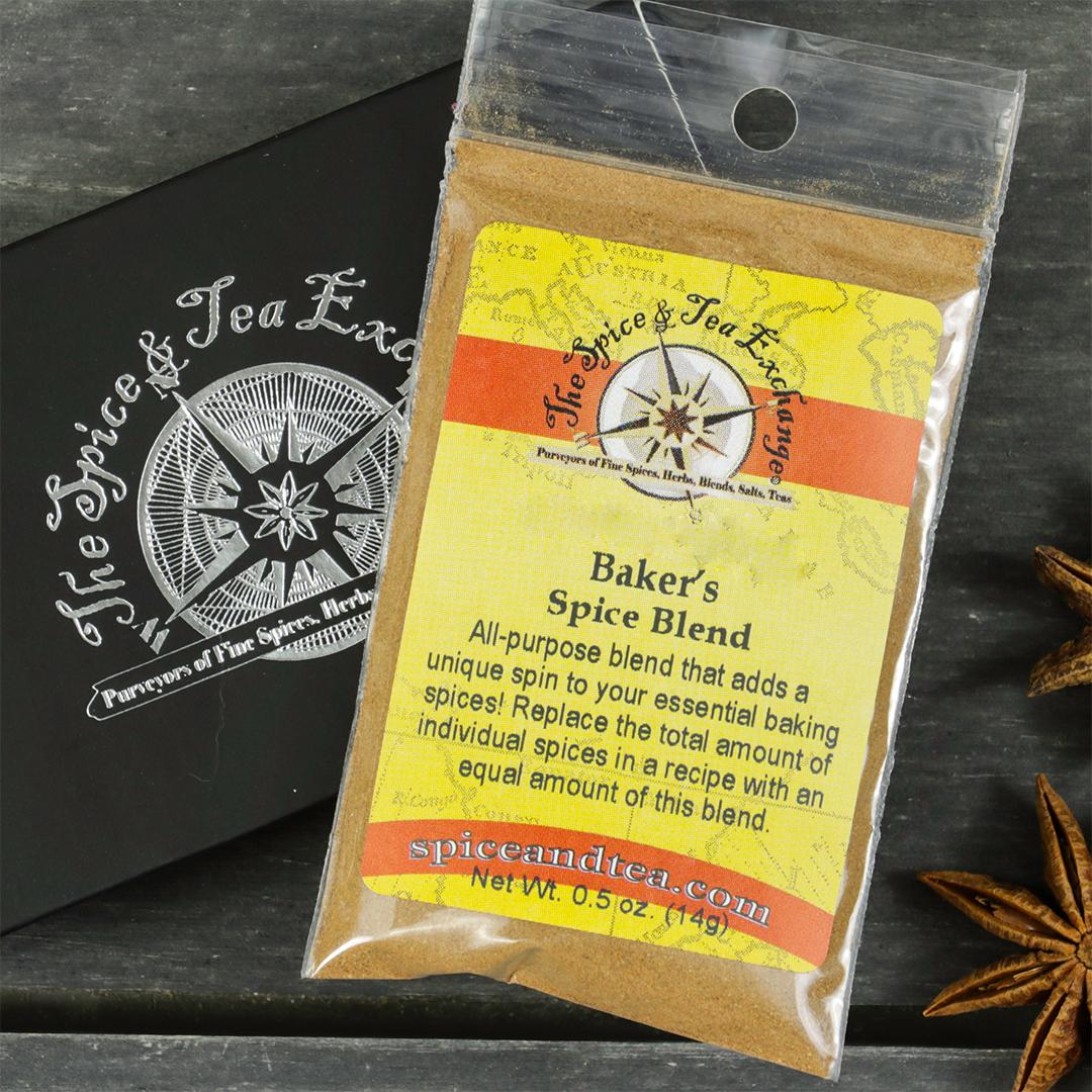 A packet of Baker's Spice Blend - Barter Box, an all-purpose baking spice, sits atop a black box with The Spice & Tea Exchange logo. The scene is accented by a nearby star anise, making it a perfect gift for baking enthusiasts.