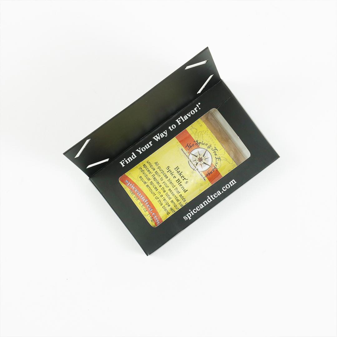 A small black Barter Box, open to reveal a Baker's Spice Blend packet labeled The Spice & Tea Exchange and spiceandtea.mom. Inside flap says "Find Your Way to Flavor!"—a perfect gift for baking spice lovers, shown on a white background.