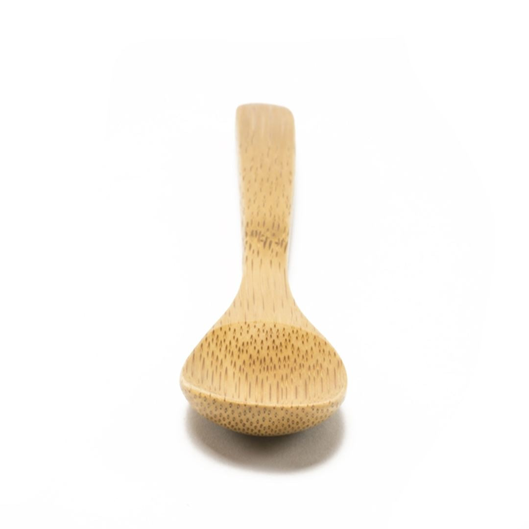 The Bamboo Salt Spoon Mini, made from light-colored Moso bamboo, is centered on a plain white background with its handle pointing away and rounded bowl facing forward—ideal as a salt accessory.
