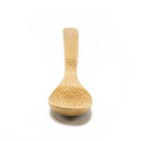 The Bamboo Salt Spoon Mini, made from light-colored Moso bamboo, is centered on a plain white background with its handle pointing away and rounded bowl facing forward—ideal as a salt accessory.