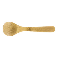 The Bamboo Salt Spoon Mini is a small, light brown spoon made from Moso bamboo with a rounded bowl and flat, textured handle—an elegant addition to your salt accessories, shown on a white background.