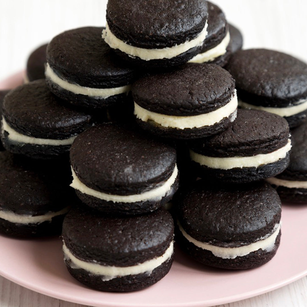 Stack of chocolate cookies with white filling on a pink plate
