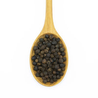 A wooden spoon filled with Smoked Black Peppercorn, photographed on a white background.