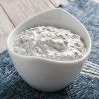 White bowl of creamy dip on a blue textured surface