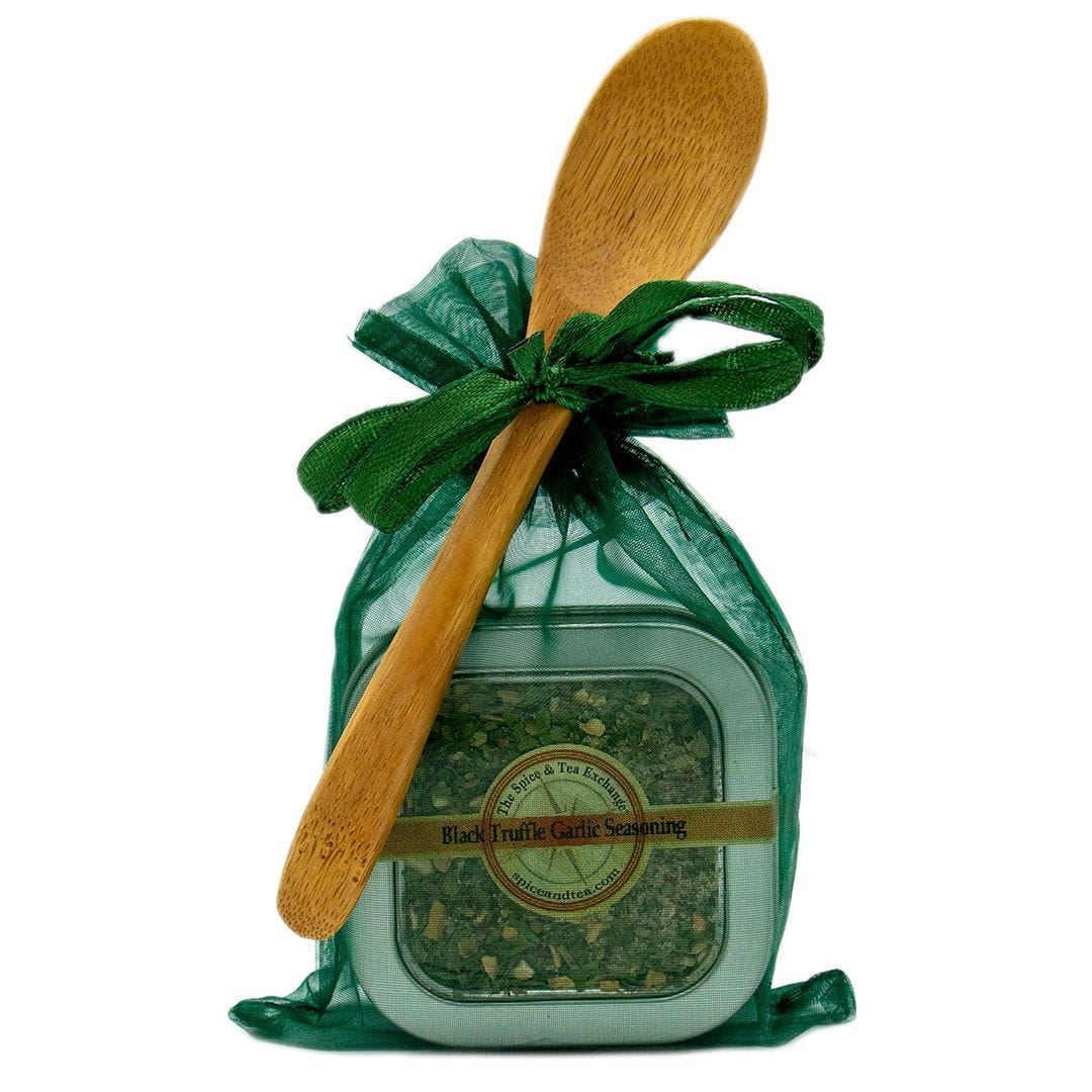A green organza gift bag holds a Black Truffle Garlic Seasoning - Spice Tin with Spoon, ideal for gourmet truffle fries, tied with a ribbon and finished with a wooden spoon.