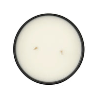 Round white candle in a black container on a white background