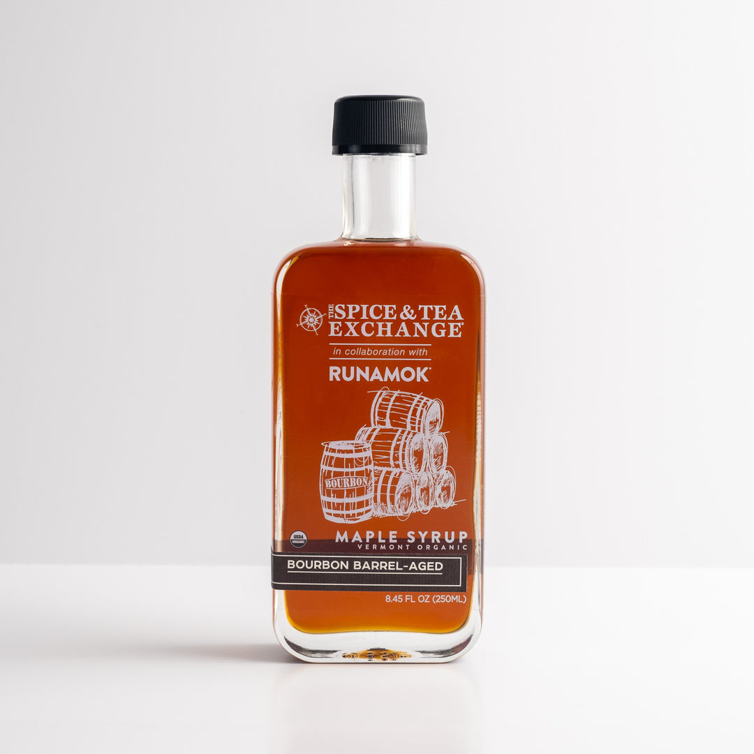 A clear glass bottle of Organic Barrel-Aged Bourbon Maple Syrup, 8.45 fl oz (250 mL), labeled Spice & Tea Exchange x Runamok, and topped with a black cap.