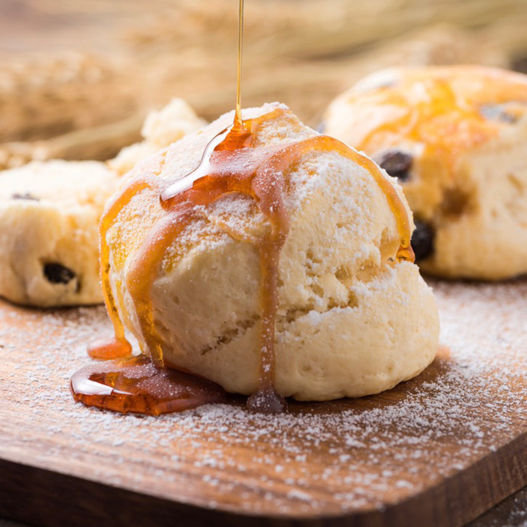 Honey drizzled over biscuits on a wooden surface
