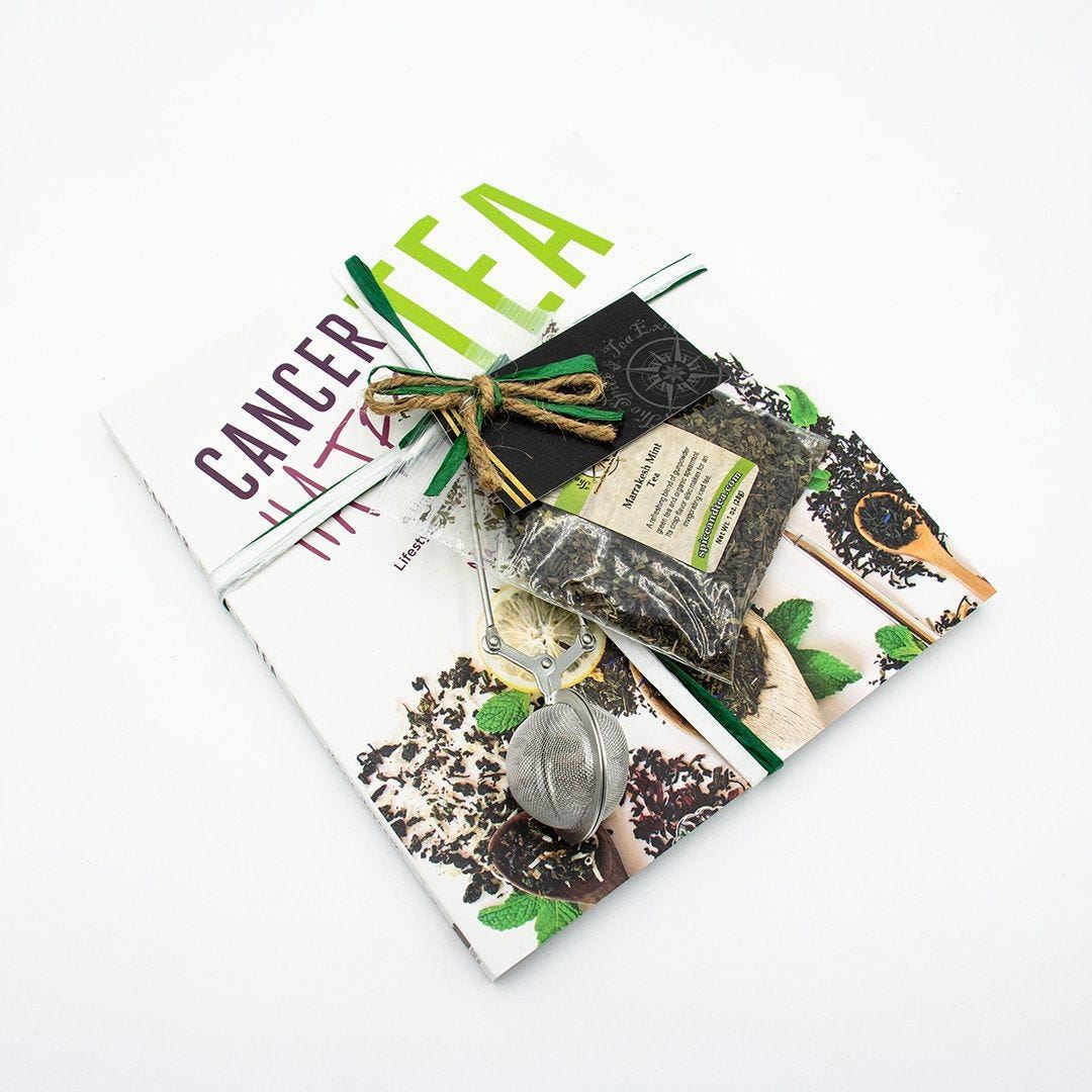 The Cancer Hates Tea Book & Bundle - Marrakesh Mint features the book, Marrakesh Mint Tea, and a metal infuser, beautifully arranged on a white background to celebrate tea and wellness.