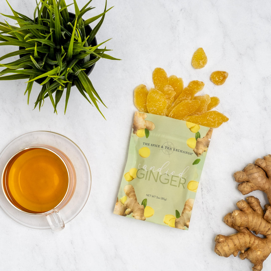 Candied Ginger - bag opened and spilling out on a white counter next to ginger tea and ginger