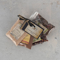 Three clear bags of Chocolate-Dipped Strawberry Tea Sampler, featuring berry bouquet and nutty chocolate mate blends, are tied with black string and labeled cards, displayed on a light gray textured surface.