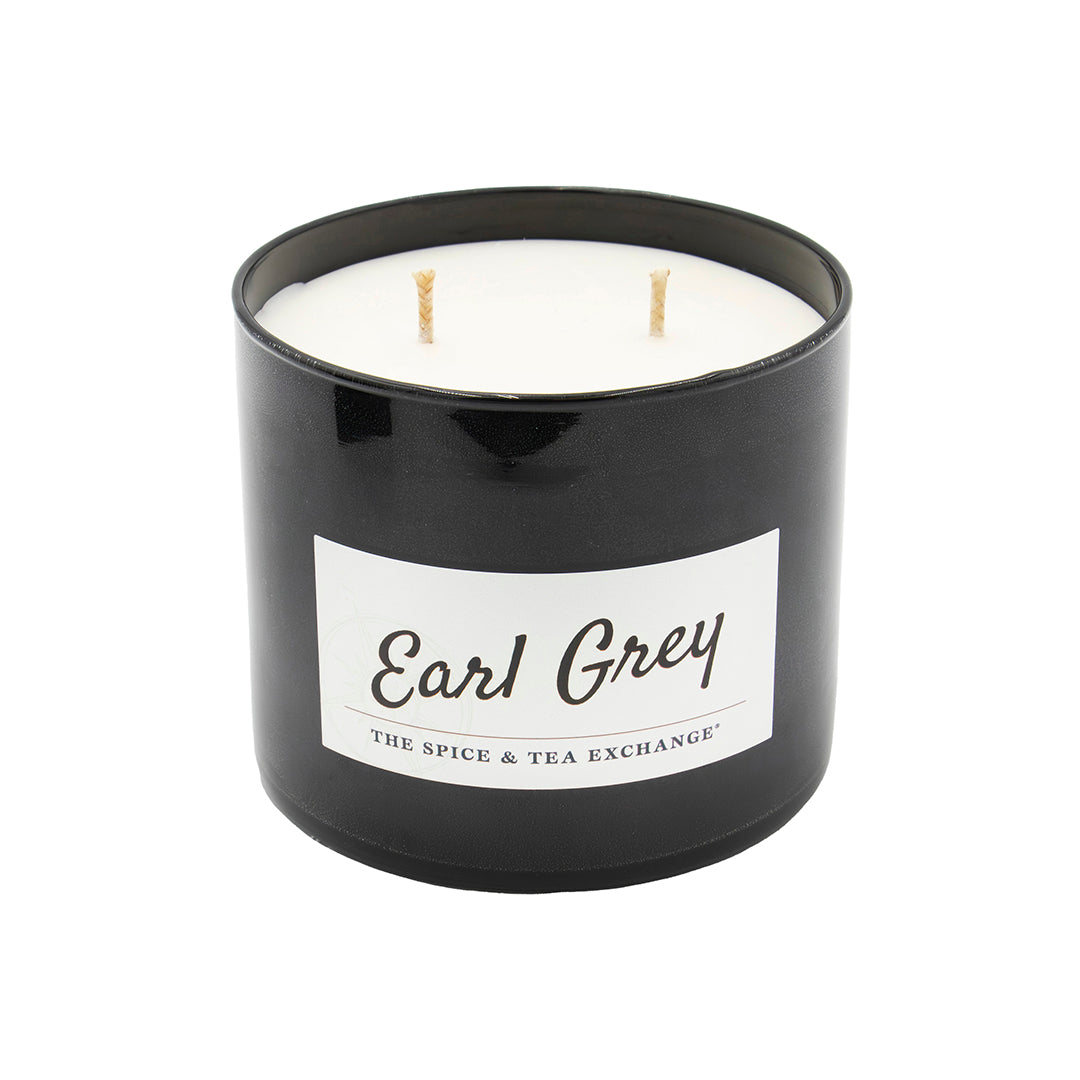 The Earl Grey Candle features a black jar with a white wax interior and three unlit wicks. Infused with essential oils, this natural soy candle from The Spice & Tea Exchange is shown on a white background.