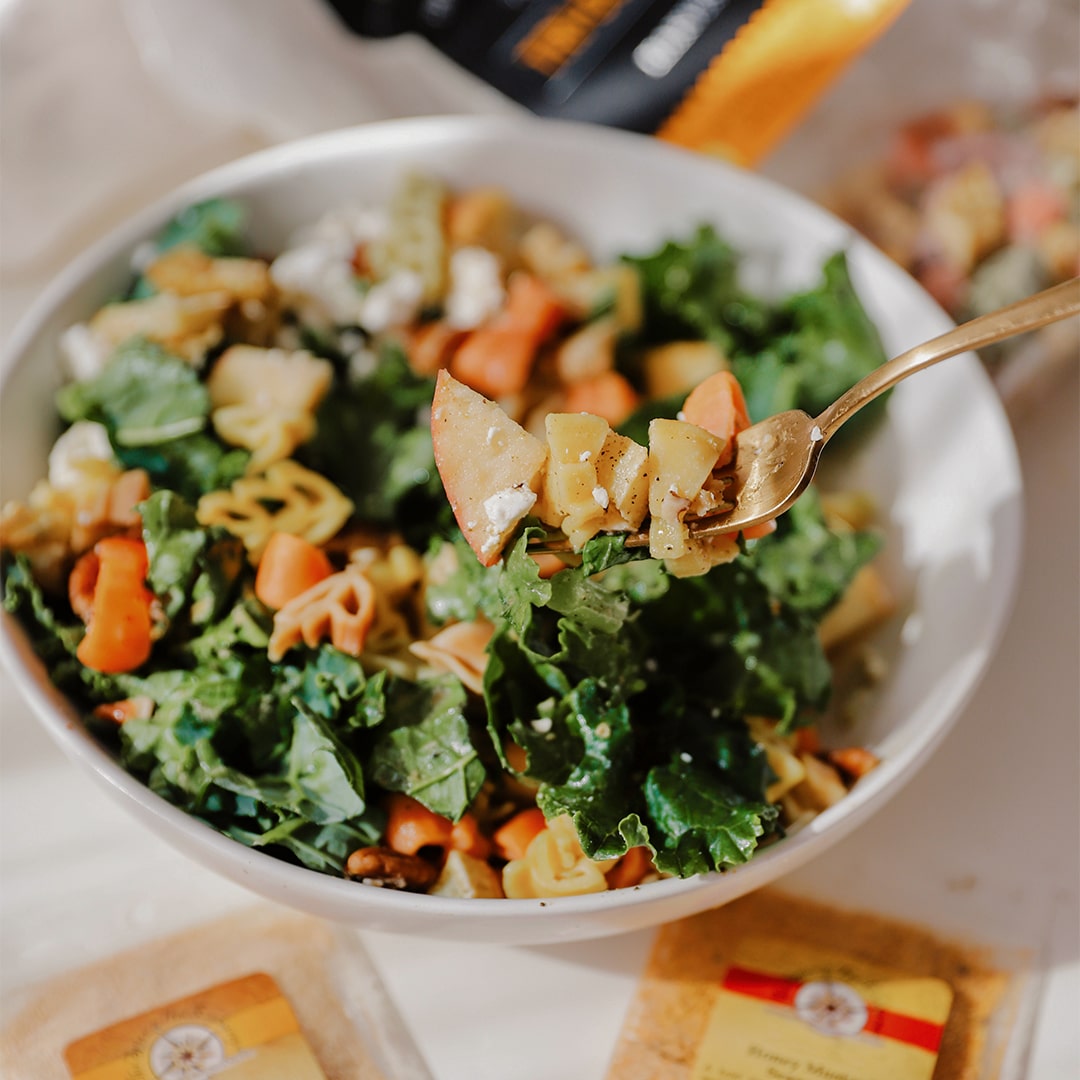 Bowl of salad with a spoonful of salad held above it, with a blurred background.