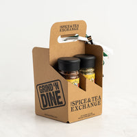 The Garlic Lover's 4-Pack Gift Box from The Spice & Tea Exchange comes in a brown cardboard carrier with black text and a handle, holding four spice jars—an ideal garlic-themed gift set.