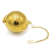 The Gold Ball Infuser - Small is a gold-colored, spherical stainless steel tea infuser featuring small perforations and a chain with a hook for hanging.