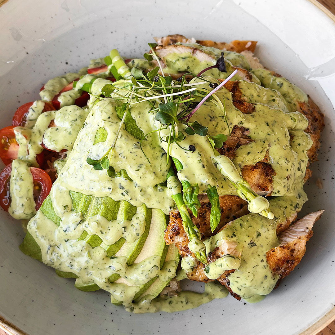 Plated dish with green sauce, chicken, and vegetables on a white plate.