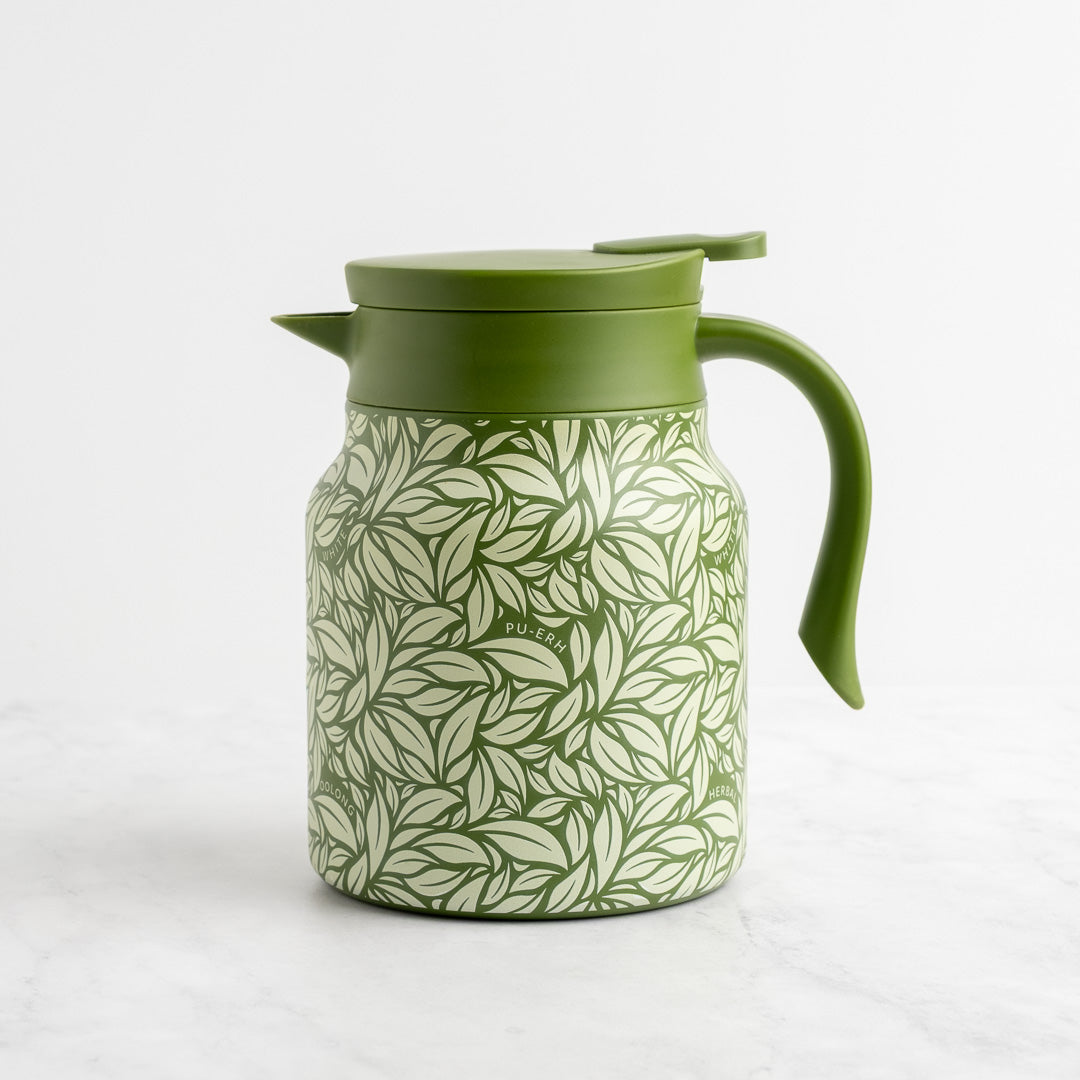 The Green Hot Tea Steeper rests on a white surface, featuring a dense green leaf pattern on its body with a solid green lid, handle, and spout—ideal for brewing loose-leaf tea.