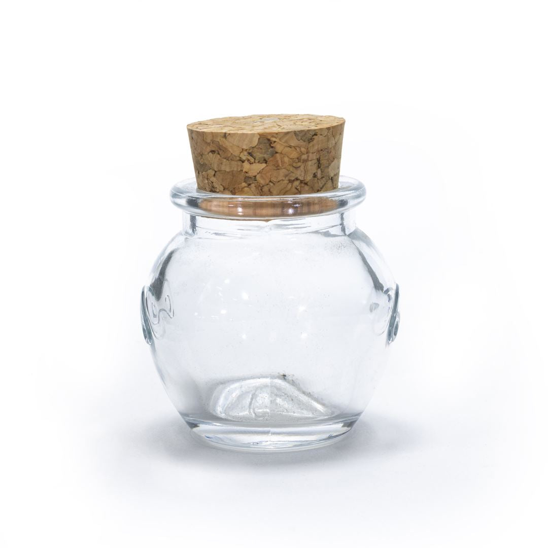The Glass Jar Honey Pot with Cork features a small, round design with a wide opening and cork lid, ideal for storing spices or showcasing small treasures.