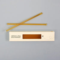 A box labeled Blackberry Blossom Honey Straws contains several honey straws, with two honey sticks above the box on a light gray background. These raw natural treats are a delicious and healthy snack option.