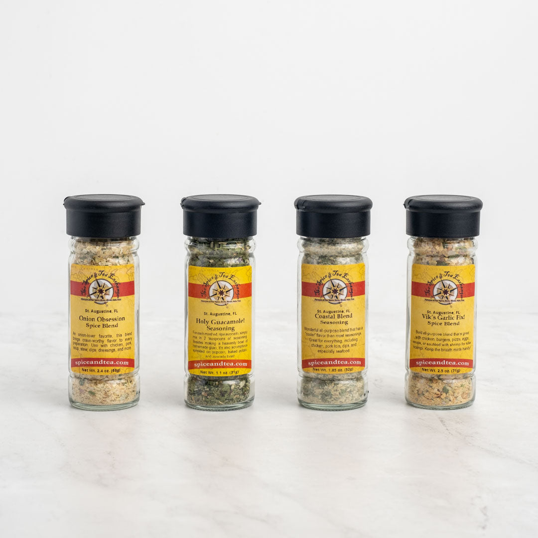 The Let's Party Dips 4-Pack Gift Set features four glass spice jars with black lids and yellow-red Spice and Tea Exchange labels, offering unique seasoning blends ideal for dip mixes or party appetizers.