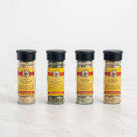 The Let's Party Dips 4-Pack Gift Set features four glass spice jars with black lids and yellow-red Spice and Tea Exchange labels, offering unique seasoning blends ideal for dip mixes or party appetizers.