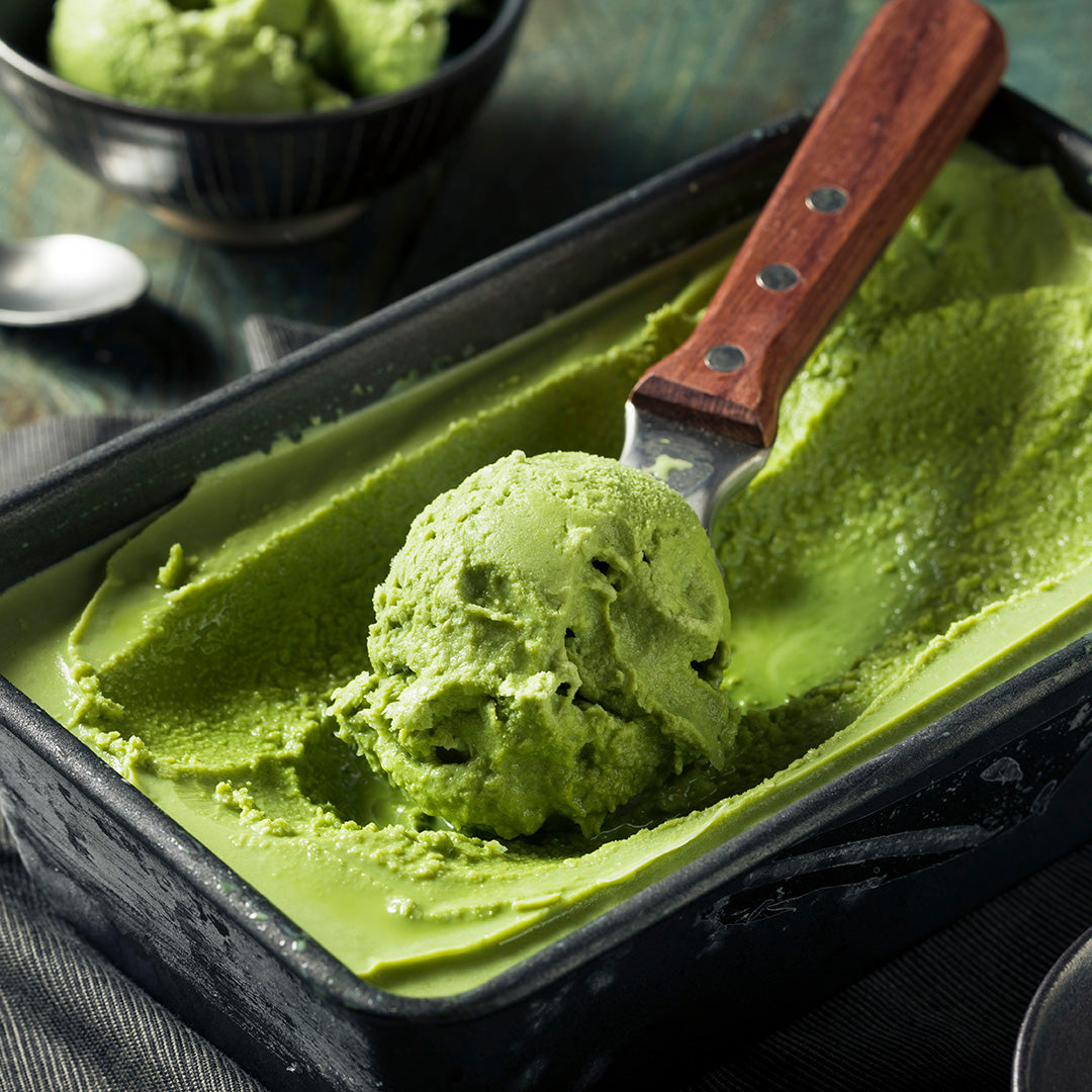 Green ice cream being scooped out in rectangular container 