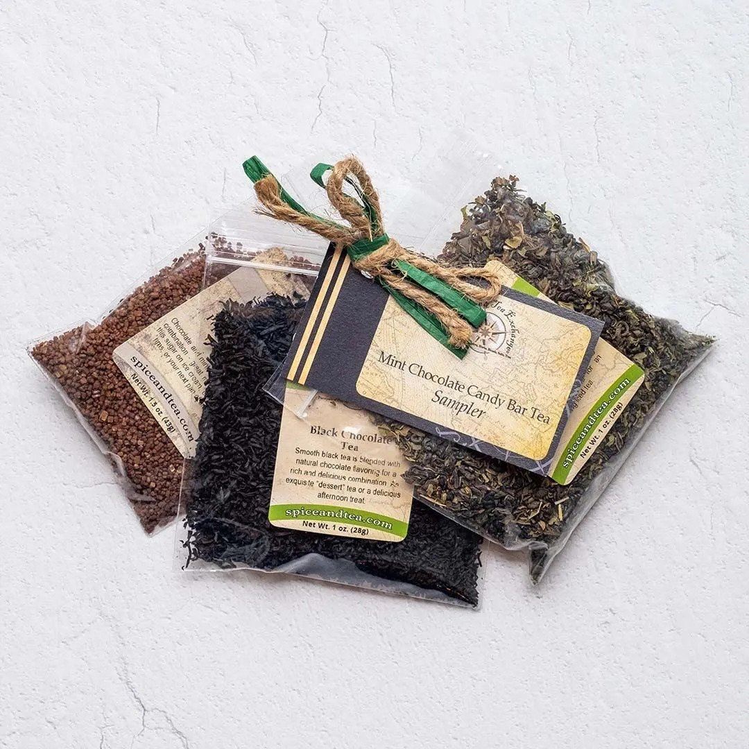 Three clear packets of loose tea leaves tied with twine and a green ribbon, each labeled and accompanied by a tag reading “Mint Chocolate Candy Bar Tea Sampler”—ideal for crafting a candy-flavored beverage.