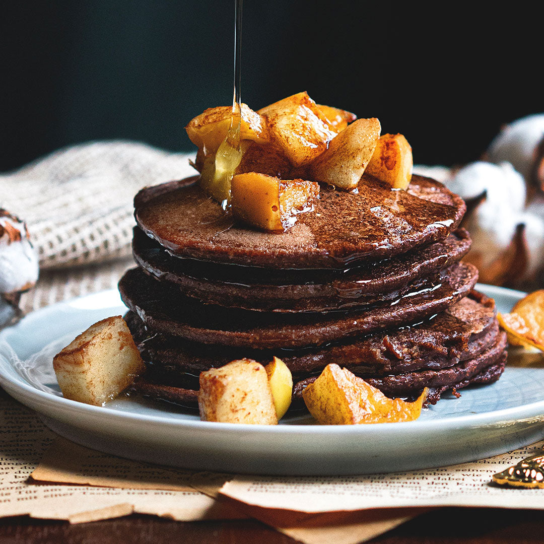 Stack of chocolate pancakes with caramelized apples on a plate