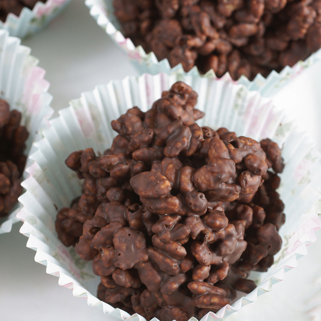 Chocolate-coated treats in a white paper cupcake liner on a light background
