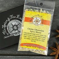 A packet of Onion Obsession Spice Blend - Barter Box rests on a dark wooden surface beside a black Spice & Tea Exchange box and star anise—an ideal gift for fans of onion seasoning.