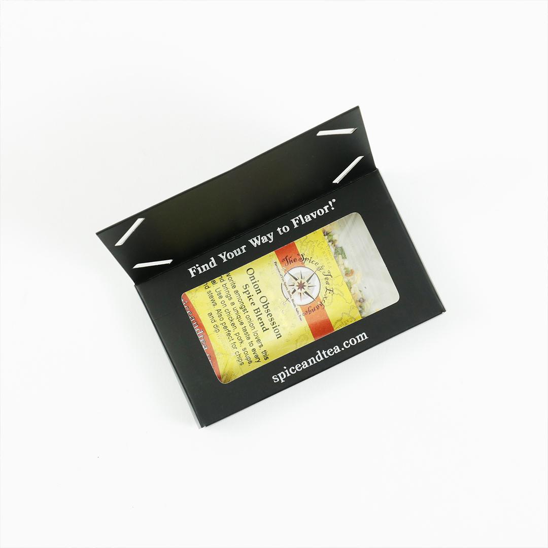A black box labeled Find Your Way to Flavor! with a window showing an Onion Obsession Spice Blend - Barter Box—perfect as a spice blend gift—from The Spice & Tea Exchange. Box includes spiceandtea.mom website.
