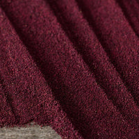 A close-up of Organic Beet Root Powder—a fine, deep purple powder—arranged in parallel ridges on a gray background, showcasing its vibrant color and natural texture.