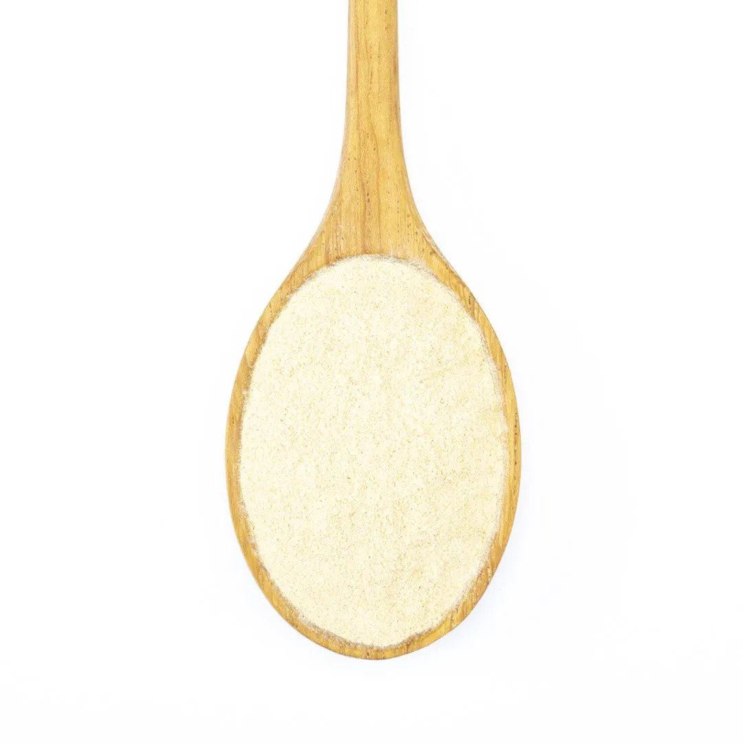A wooden spoon holds fine, light-colored Organic Peruvian Maca Powder, a renowned adaptogen, displayed on a white background.