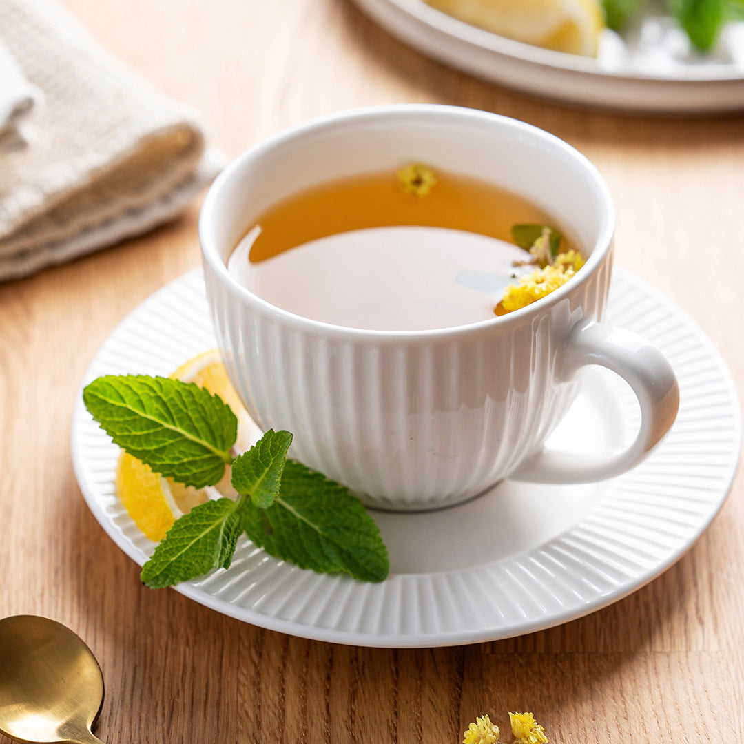 White teacup with lemon and mint on a wooden table
