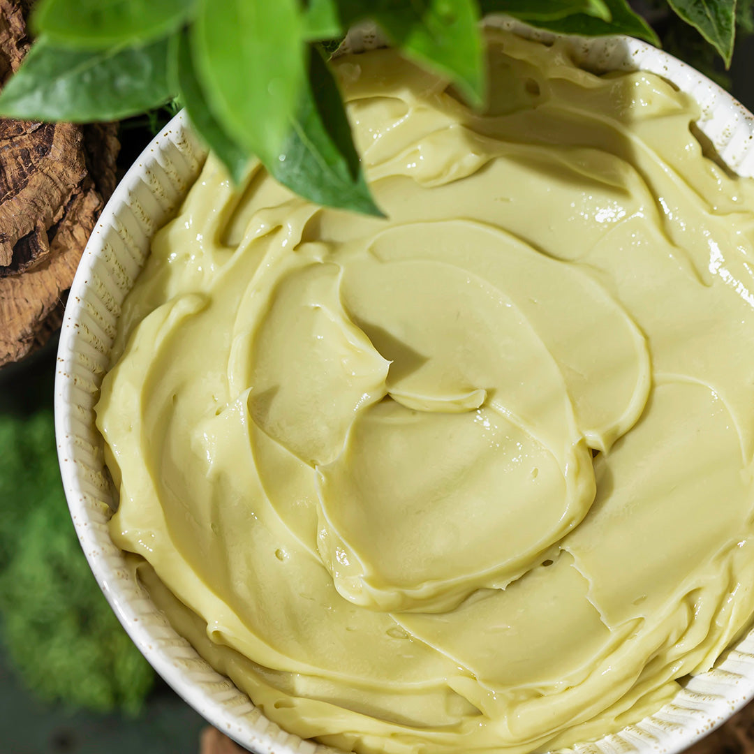 Green creamy substance in a bowl with leaves in the background