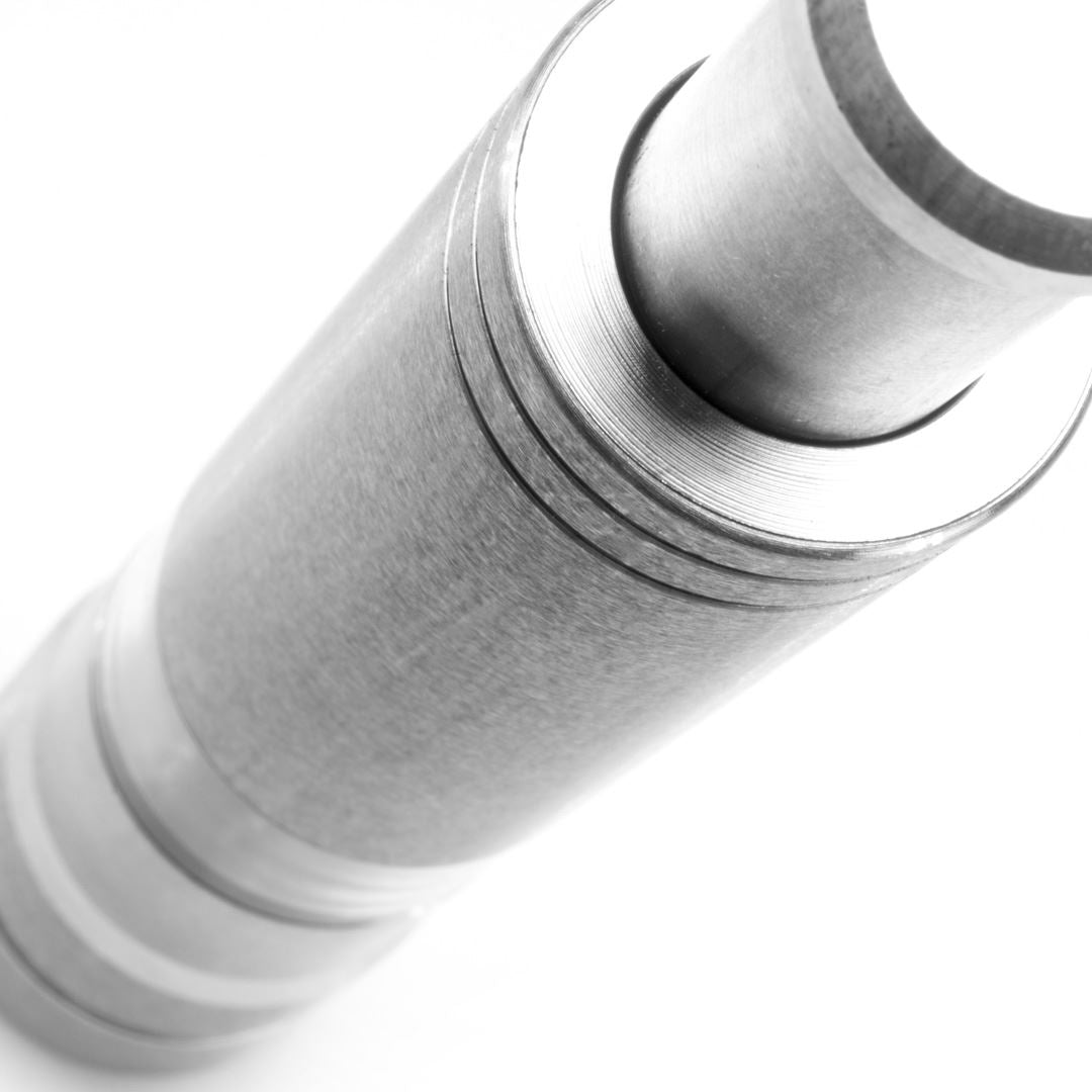 Close-up, angled view of the compact Pump & Grind Salt & Pepper Mill featuring grooved, smooth stainless steel surfaces against a white background, highlighting its textured and modern industrial design.