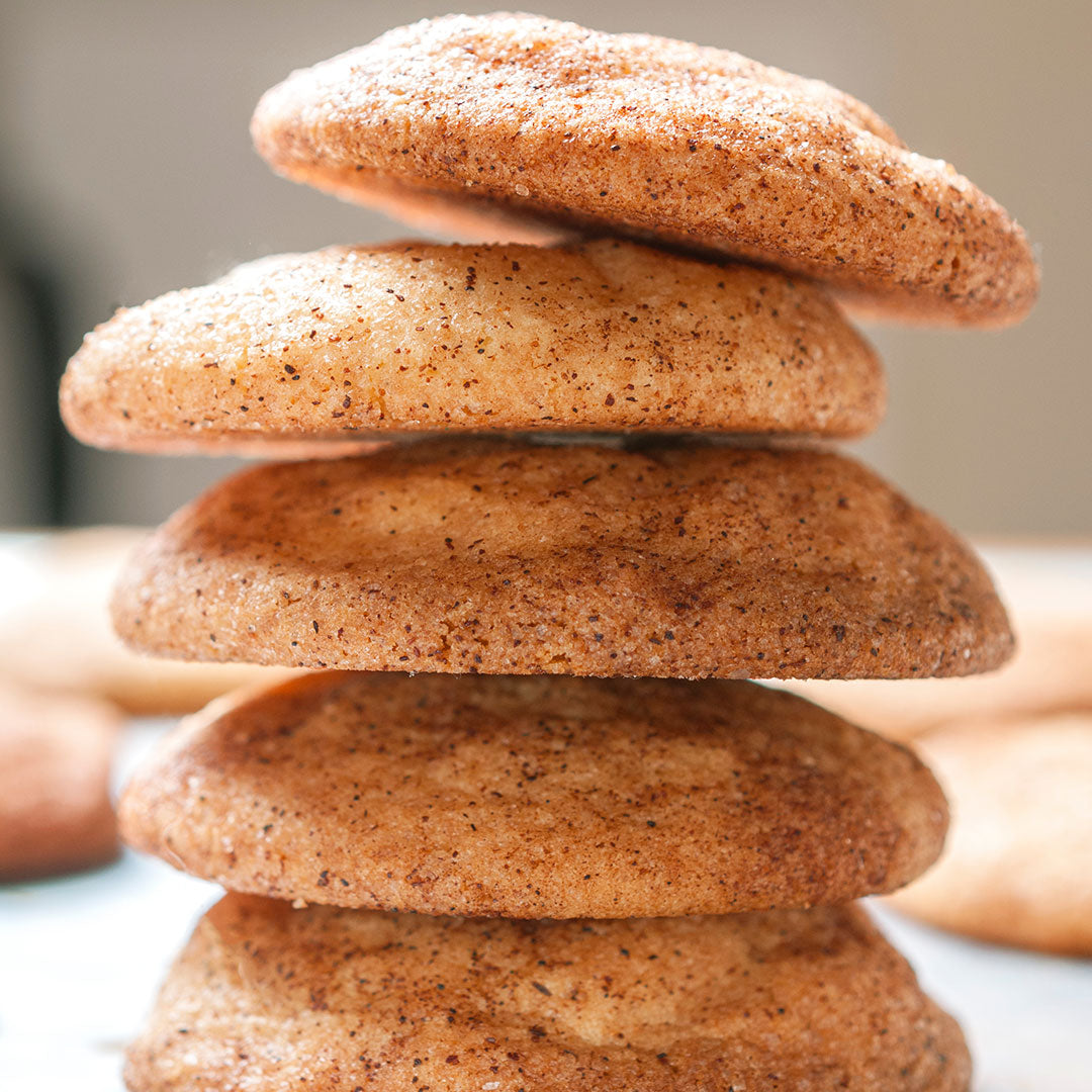 A close-up of five golden-brown snickerdoodle cookies stacked together highlights their soft texture and cinnamon-sugar coating made with Pumpkin Spice Monk Fruit Sweetener, a tasty sugar substitute.