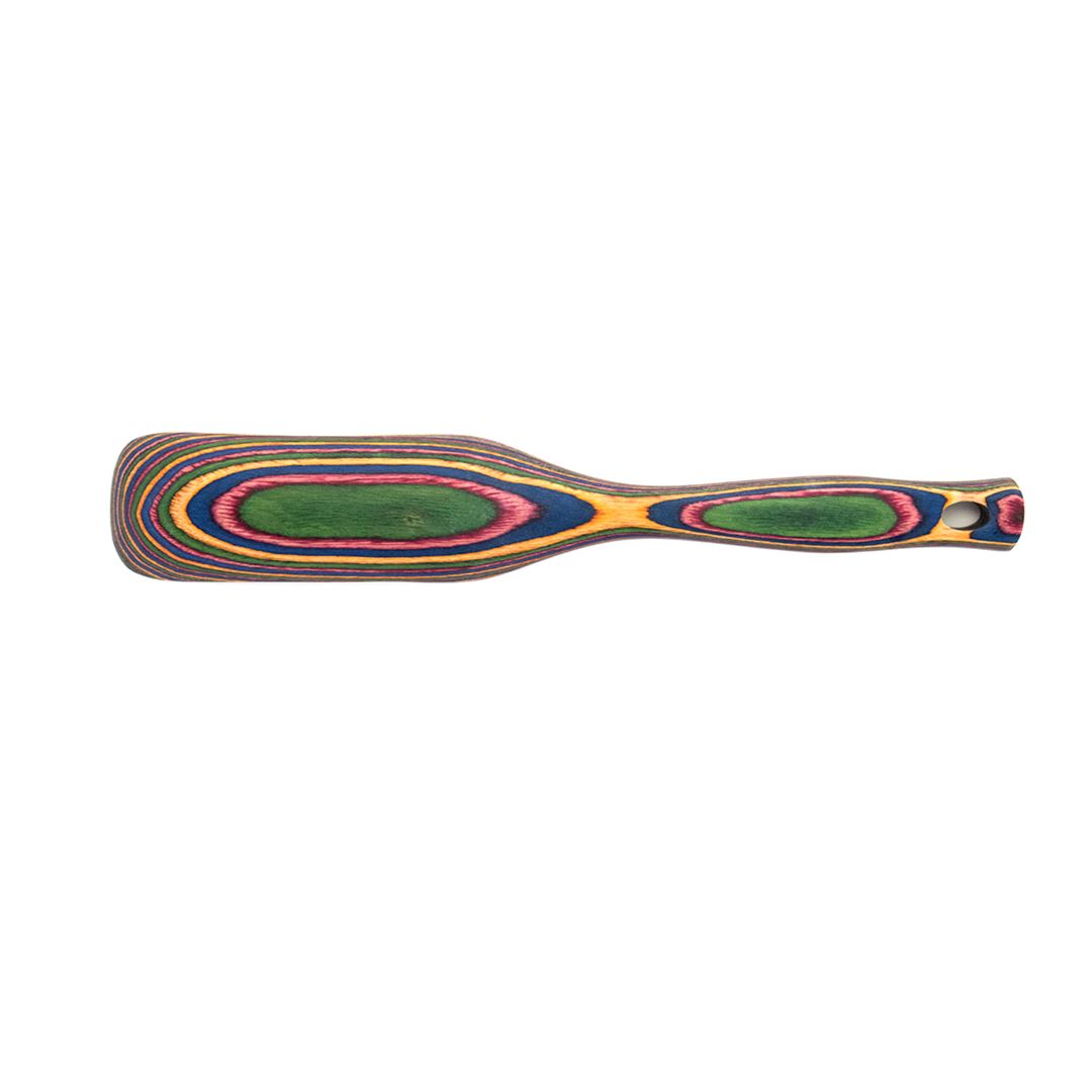 The Rainbow Spurtle is a flat, rectangular utensil with a rounded handle, made from layered, colorful pakkawood in yellow, green, pink, blue, and brown. It's durable and safe for use with non-scratch cookware.