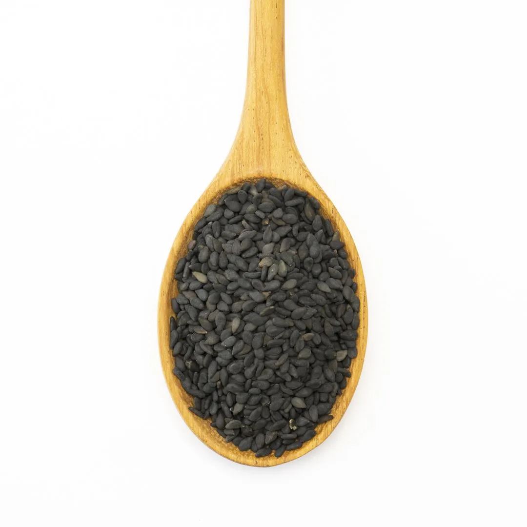 A wooden spoon filled with Sesame Black Seed, prized for its nutty oil flavor and popular in sushi dishes, is displayed on a white background.
