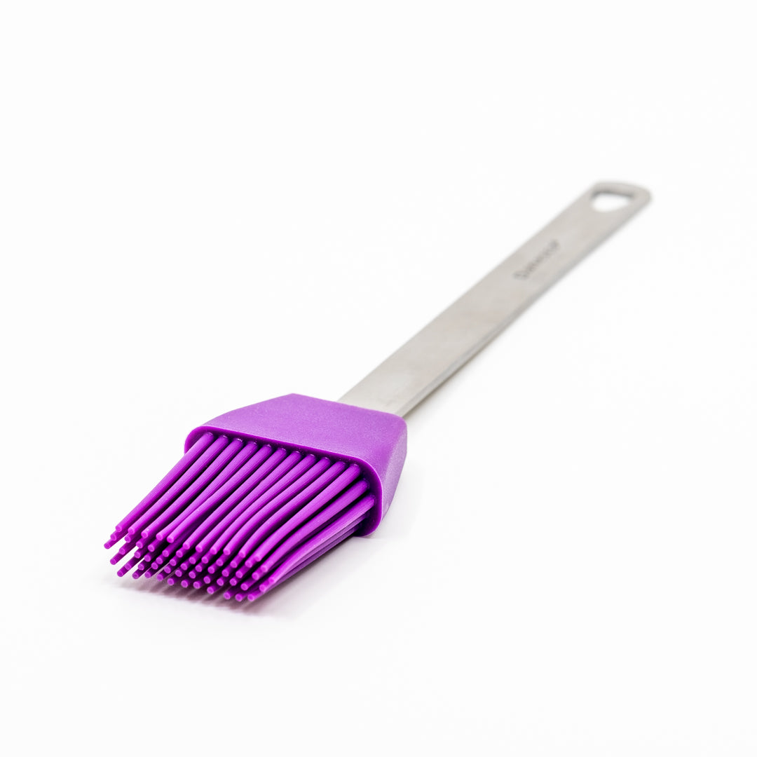 The Mini Basting Brushes feature a purple silicone head and bristles with a stainless steel handle, shown on a white surface—ideal for grilling gifts or enhancing your basting brush collection.