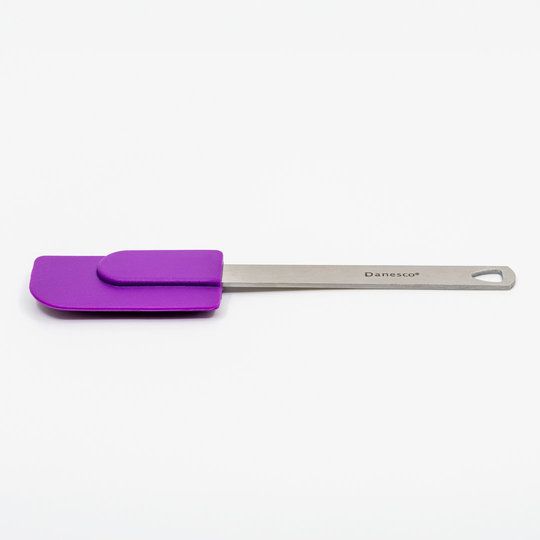 A Mini Spatula with a purple silicone head and stainless steel handle, branded Danesco, features a hanging hole at the end and is displayed on a plain white background.