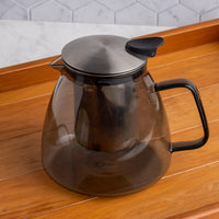Stormy Glass Teapot with metal lid on a wooden surface