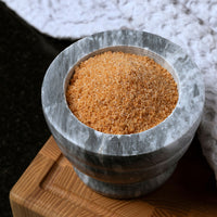 A marble mortar filled with French Fry Seasoning - Sweet 'n Smoky sits on a wooden board, with a textured white cloth in the background.