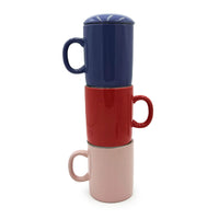 Stack of three ceramic mugs in blue, red, and pink on a white background