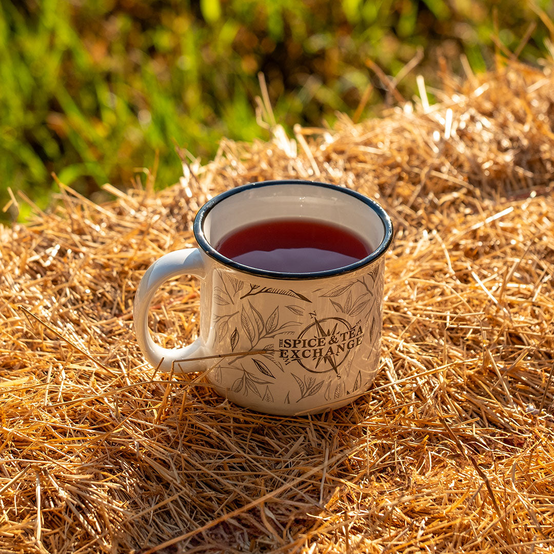 Tea mug with a floral design on a bed of straw outdoors