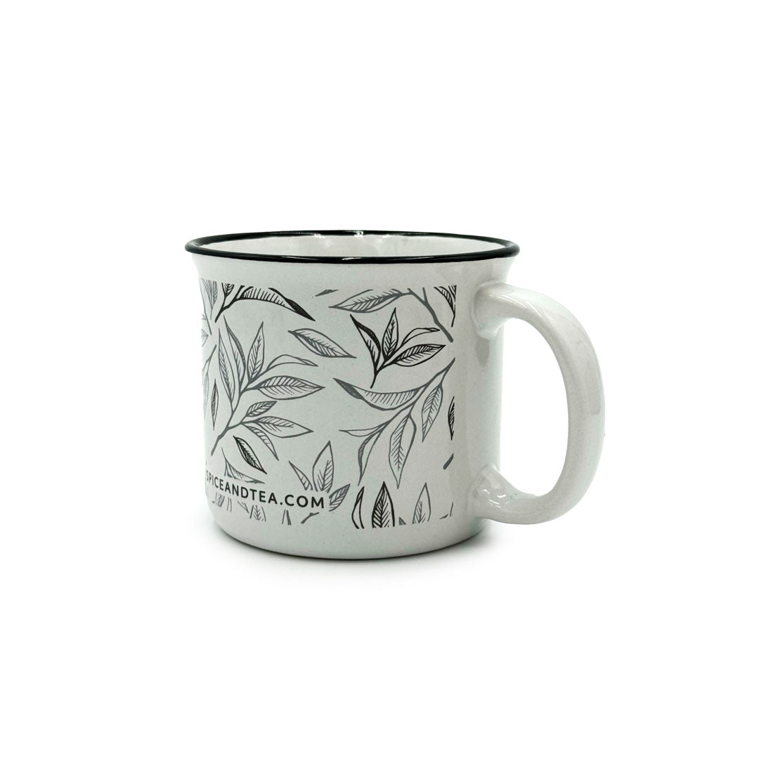 The Tea Leaf Ceramic Camp Mug is a 12-ounce ceramic mug with a black rim and handle, featuring a black line tea leaf design and a website URL near the base.