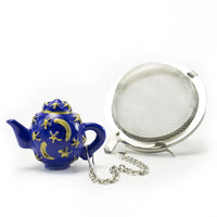 The Infuser with Teapot Charm features a blue teapot-shaped charm adorned with gold stars and moons, attached by a silver chain to a metal mesh tea ball infuser, shown on a white background.